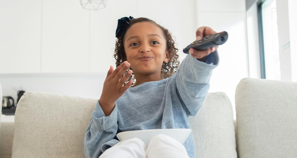A child using a TV remote on the sofa